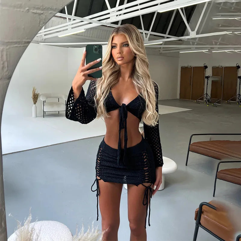 Woman in a black crochet cover-up standing in a modern indoor setting. front view